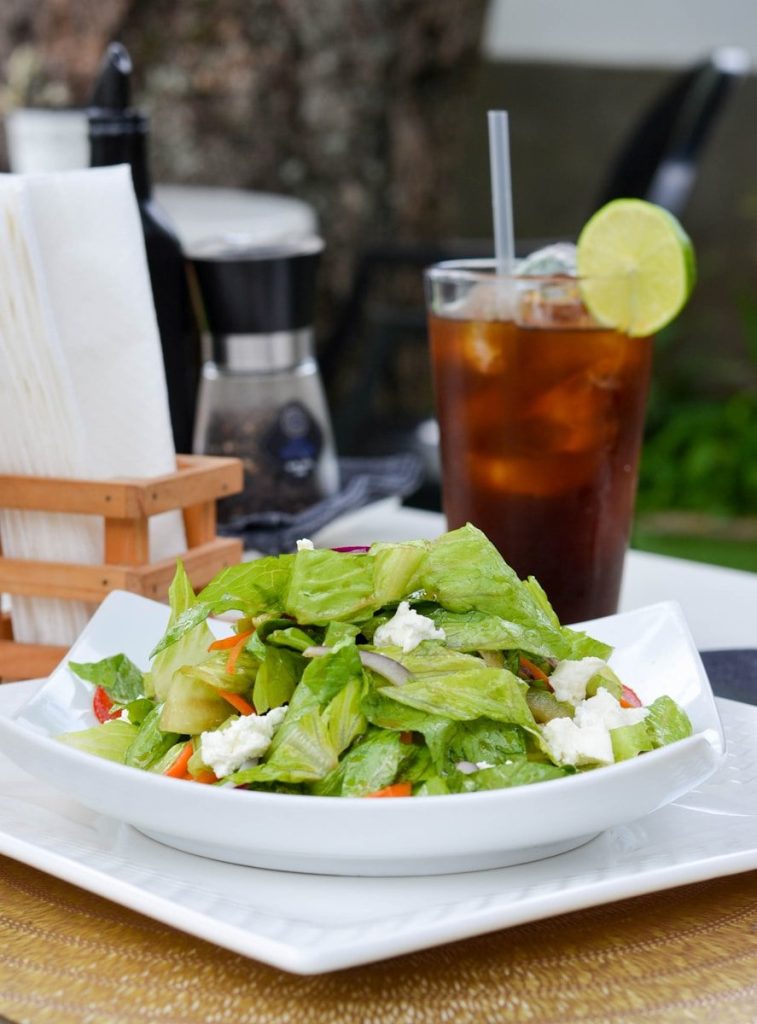 a white plate topped with a salad next to a drink